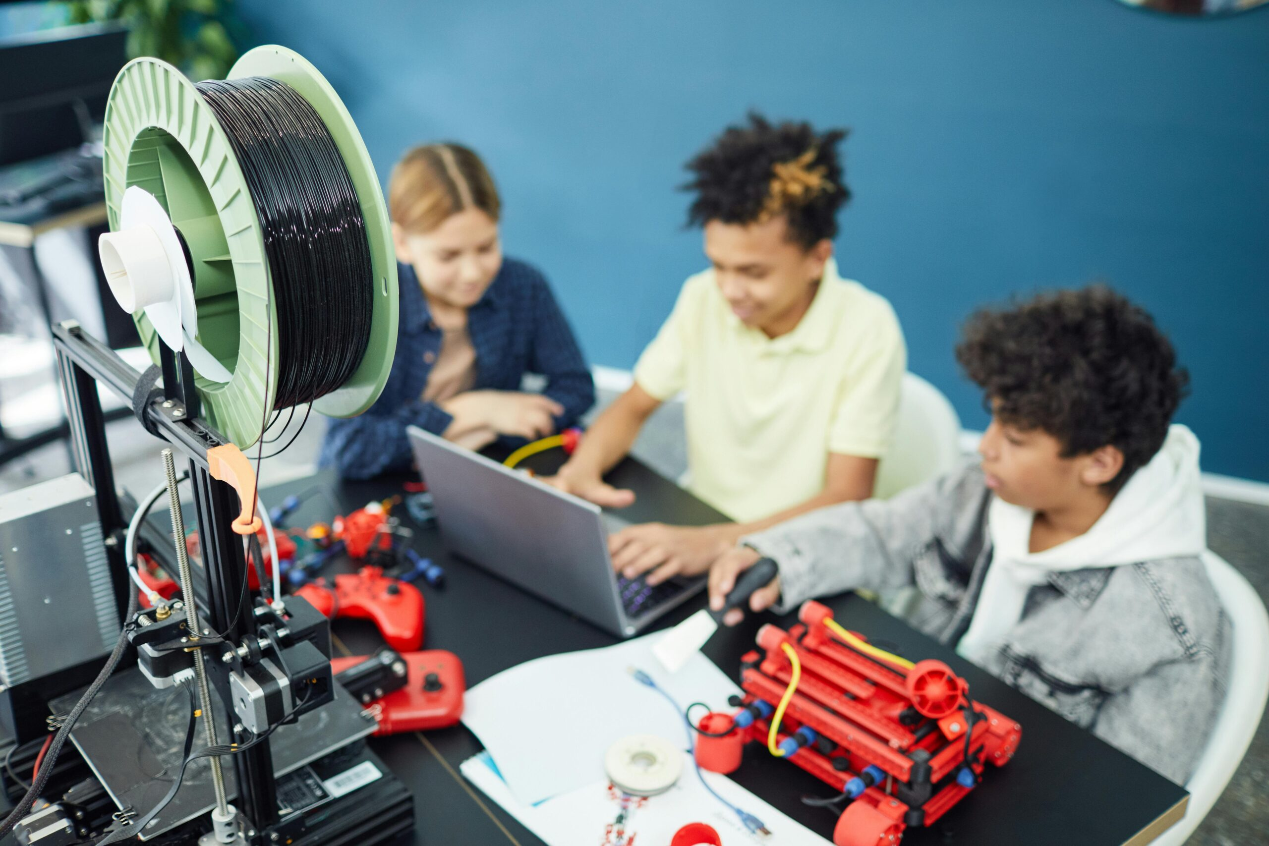 Students collaborating on a STEM project using 3D printing technology, computer-aided design software, and hands-on engineering concepts in a classroom environment.